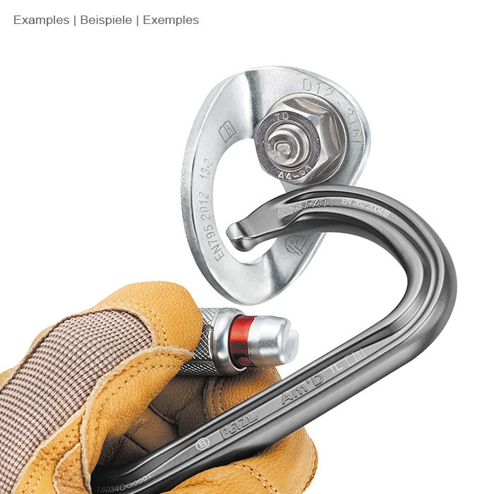 Coeur Stainless 12 by Petzl, silver metal part with snap hook, held by one hand with yellow work glove and black snap hook with red locking mechanism
