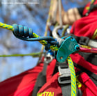 Flexbee blue belay device with blue and yellow climbing rope, attached to a person with a red climbing outfit
