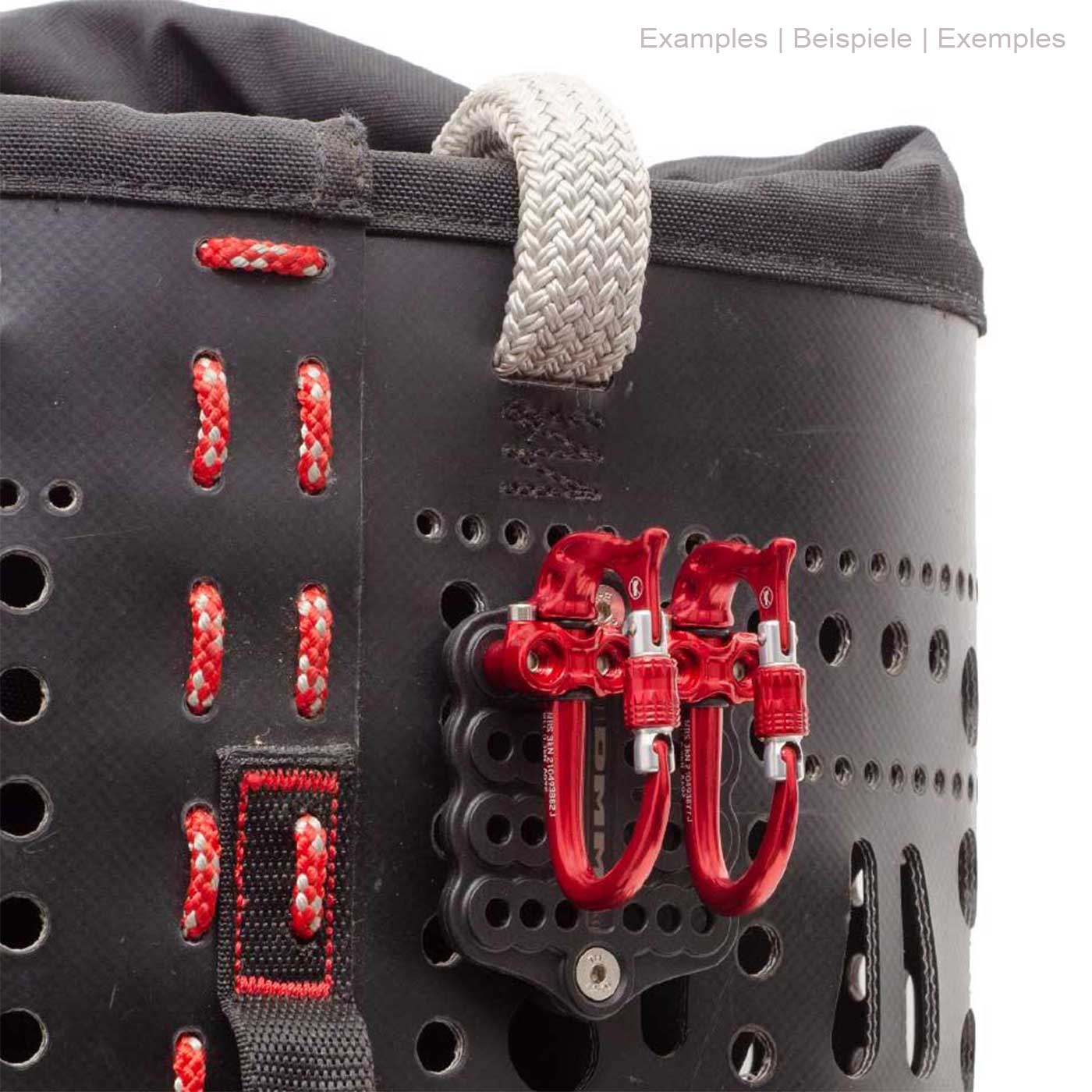 DMM Parking Lot, black plate with several round holes, attached to a black bag with red stitching and two silver carabiners with red clasps
