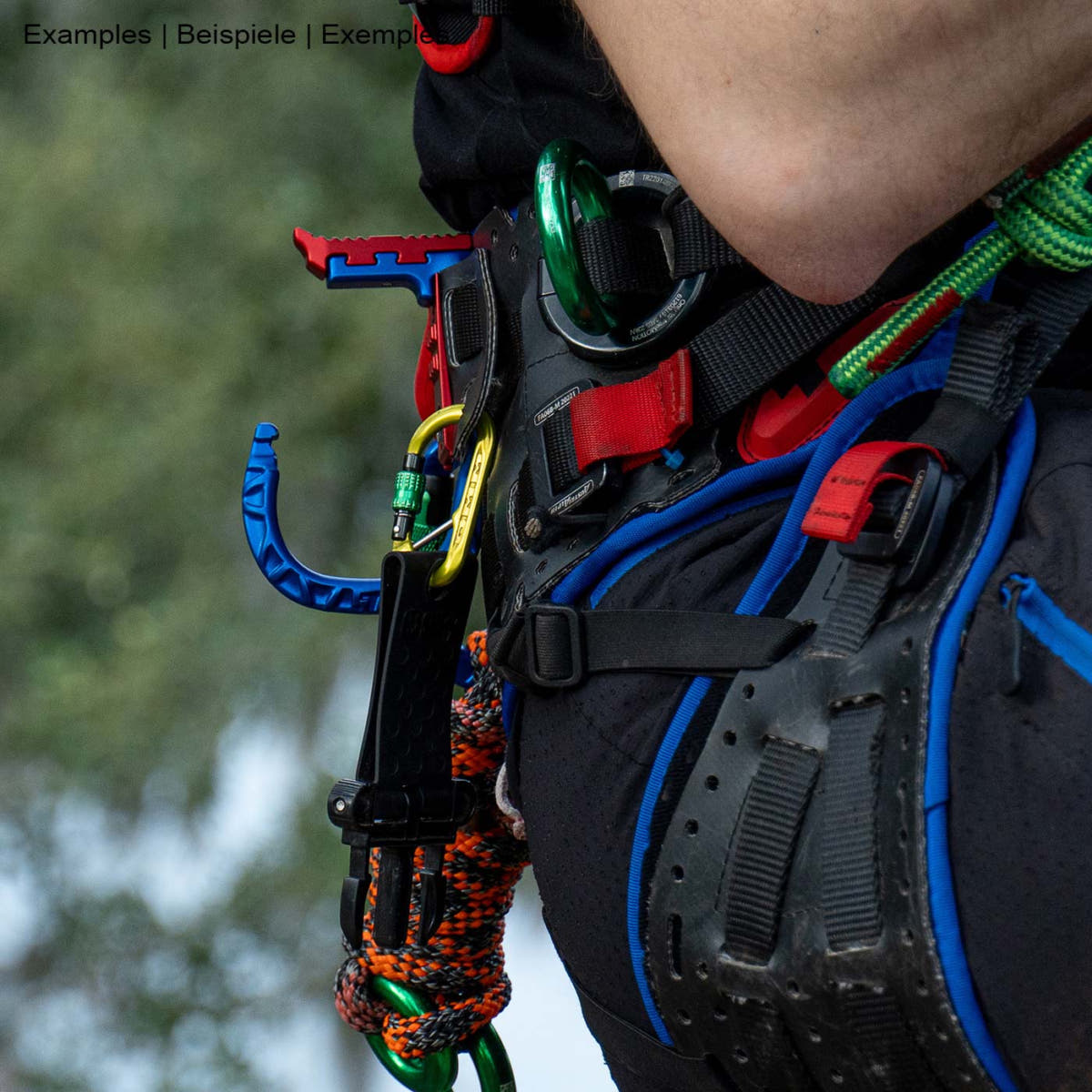 skyHOOK Open Gate in blue and red attached to a climbing harness, in use by a person with climbing equipment