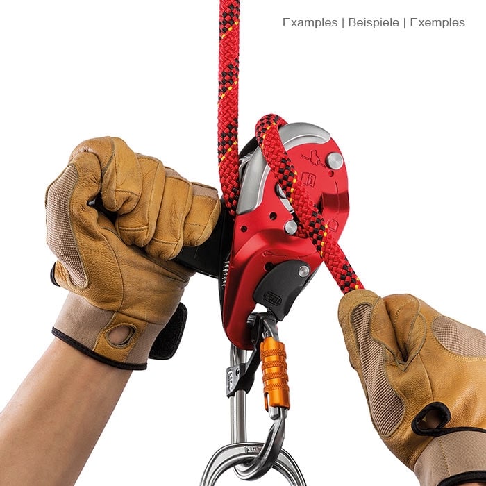 I'D L by Petzl, the climbing frame is held by two hands with brown gloves, a red rope is threaded and a carabiner hangs at the bottom