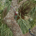 canopyANCHOR Thimble made of black-white-red rope with metal eyelet, attached to a tree trunk with other colorful ropes and climbing equipment