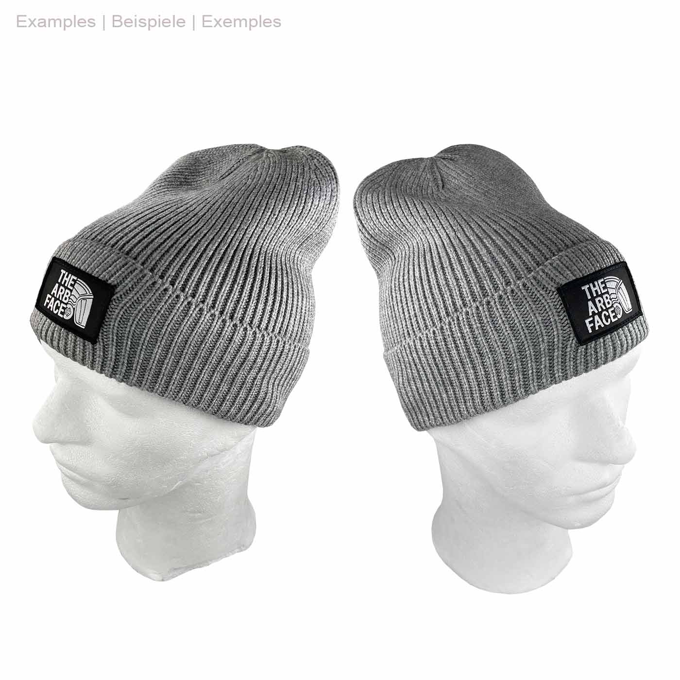 Gray Arbface Beanie Hat with Black Logo Patch on Front, Shown on White Window Head from Two Different Perspectives