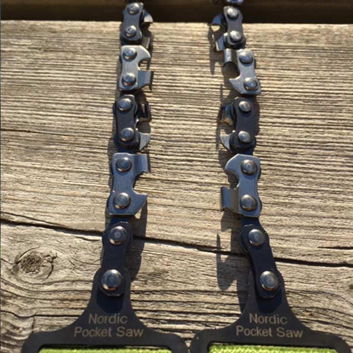 Close-up of the Nordic Pocket Saw chain with the lettering on the black handles, lying on wood