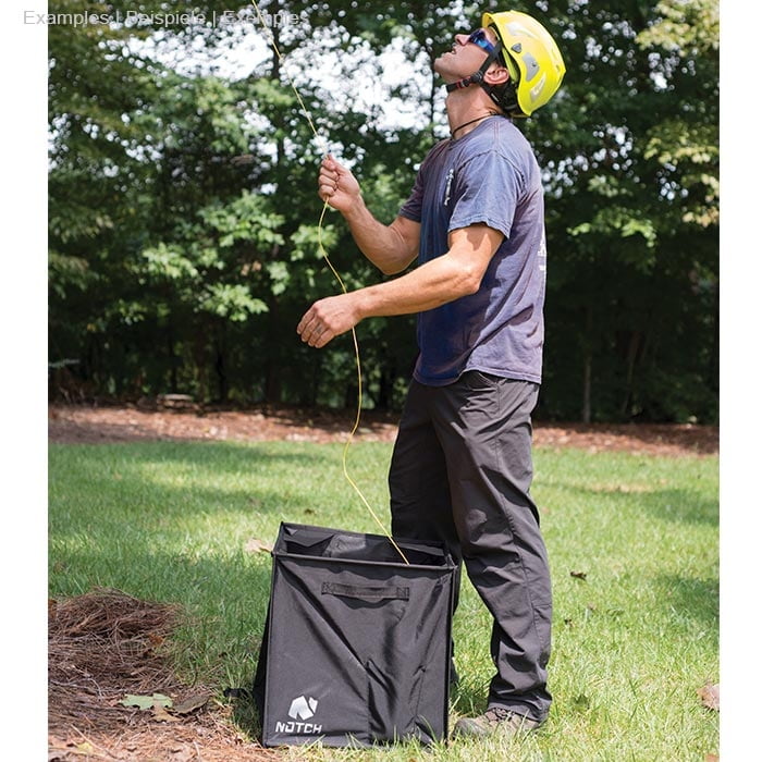 Man in yellow helmet and sunglasses standing on grass and holding orange rope over a black Pro Folding Cube of Notch