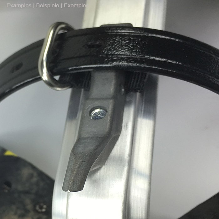 Thistle guide eye for leather strapping attached to a black leather strap wrapped around a silver metal part, visibly attached to the metal part with a screw