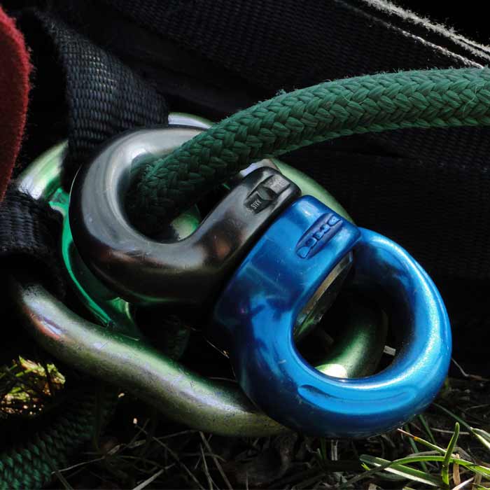 Axis Swivel S, swivel connection point in blue and black connected to green rope and other metal accessories on grass floor