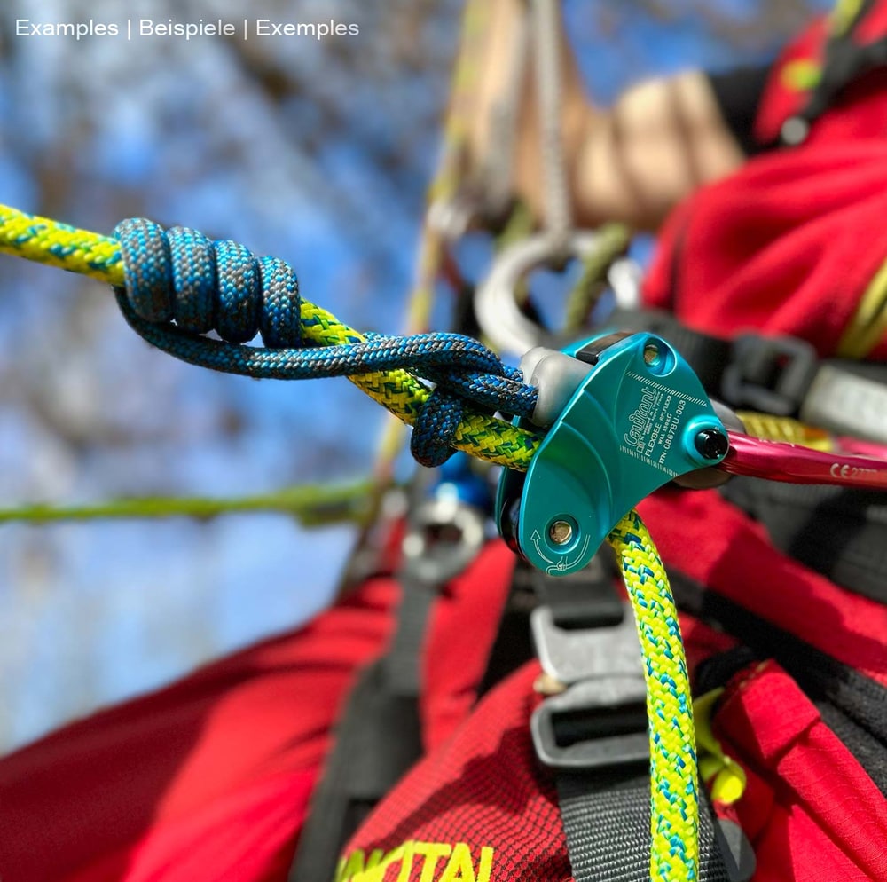 Flexbee blue belay device with blue and yellow climbing rope, attached to a person with a red climbing outfit