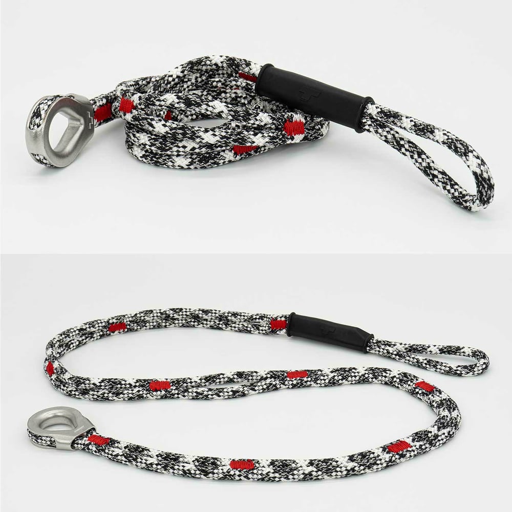 canopyANCHOR Thimble made of black, white and red rope with metal eyelet and loop, lying on a white background