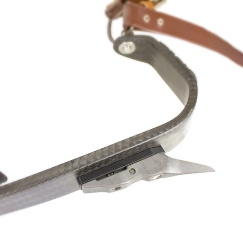 Close-up of a curved carbon part with brown leather strap and metallic fastener