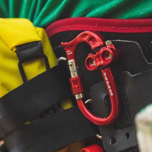 Micro Vault by DMM, red carabiner with screw closure attached to a black backpack strap