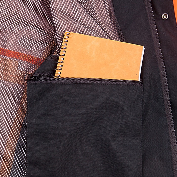 Inside of the Keiu rain jacket with black zipper pocket containing an orange notebook