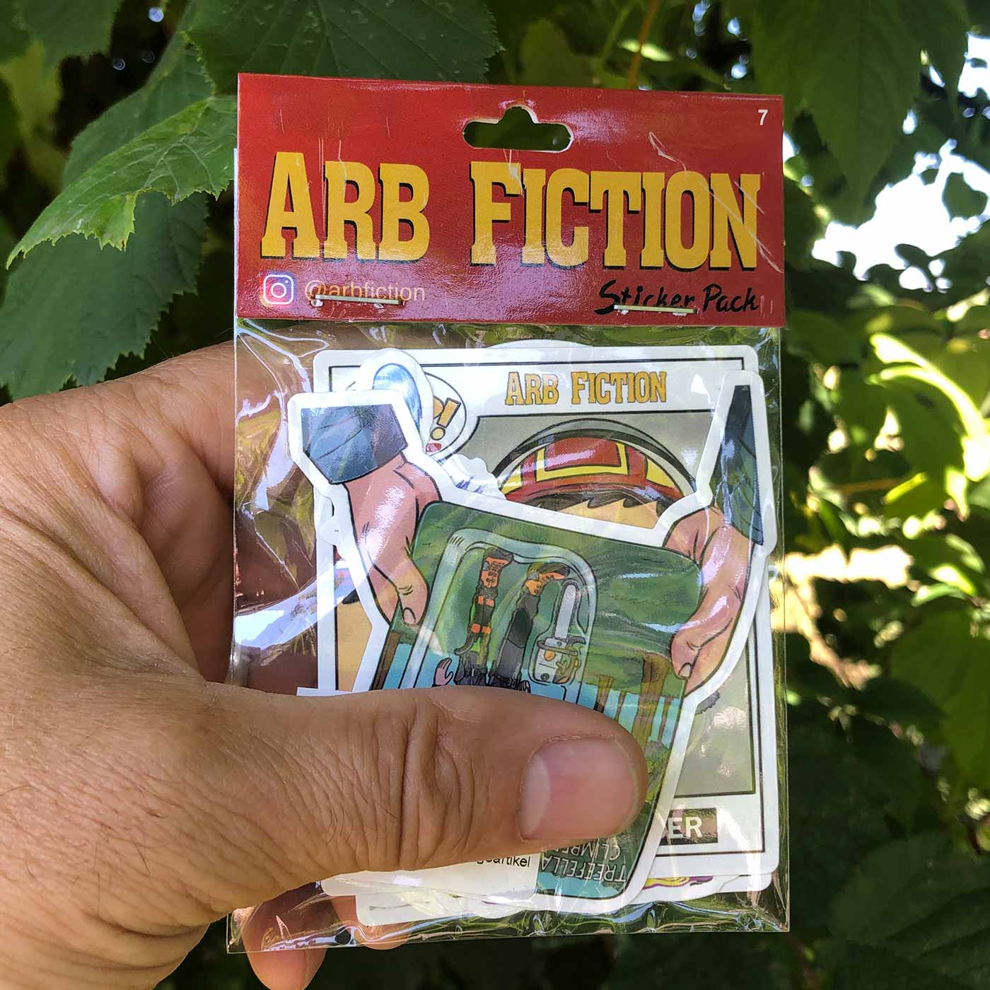 Hand Holding ARB Fiction Pack Vol. 7 Sticker Pack with Multiple Stickers, Including a Tree Climber and a Character with Helmet, Manufacturer ARB Fiction