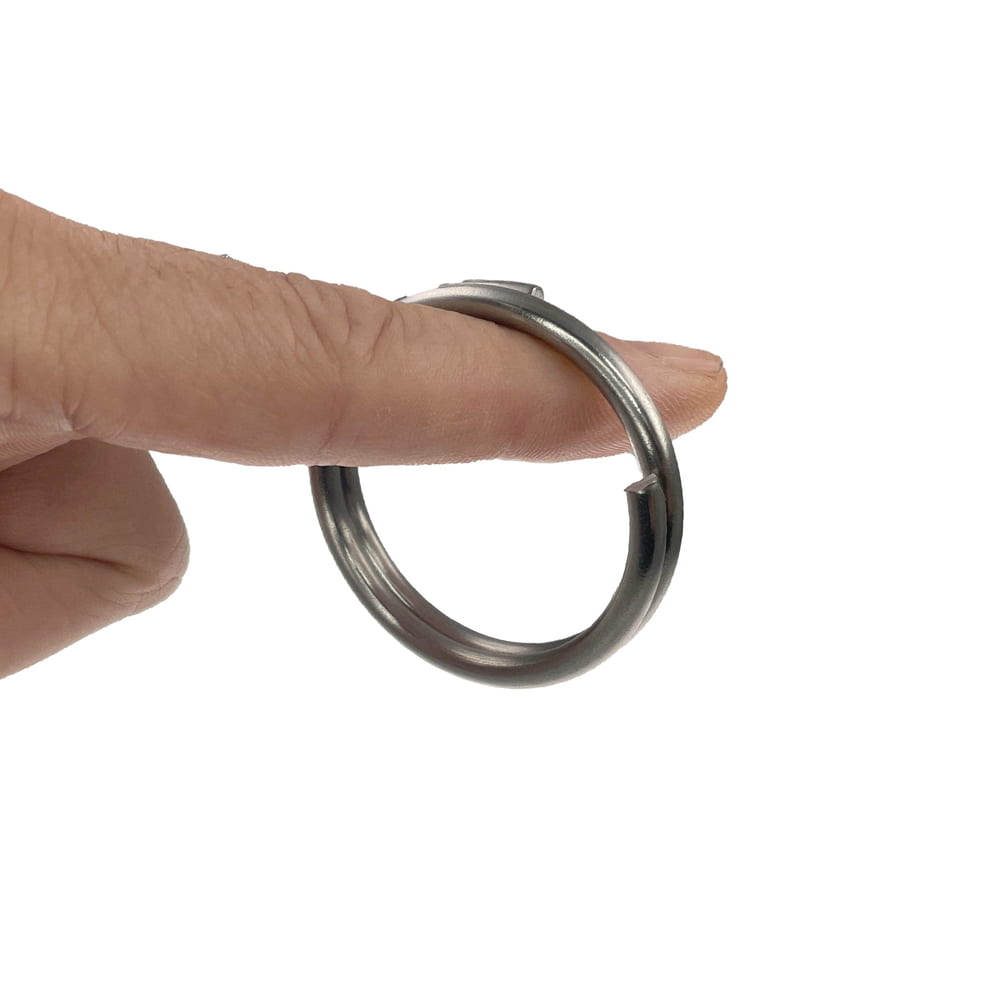 Spring ring 40 mm, silver metal ring with a spiral opening, held by a finger against a white background
