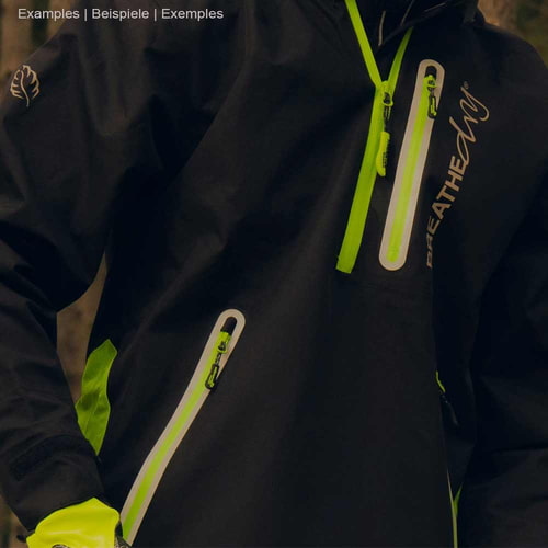 Close-up of a person wearing black BreatheDry smock jacket with green details and zippered pockets