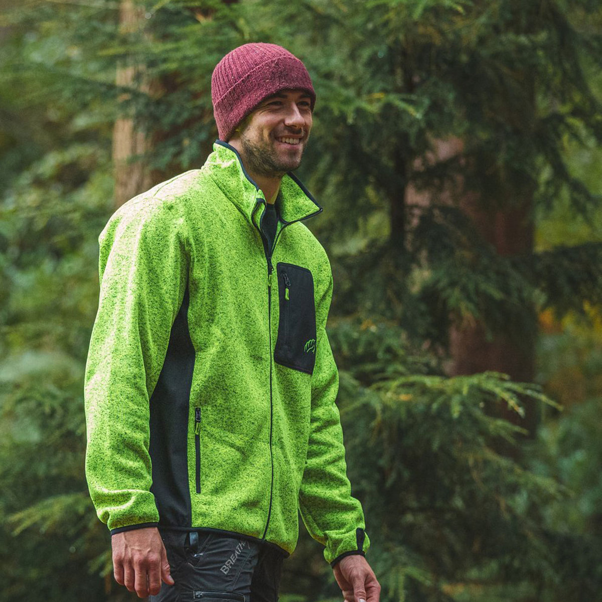 Man wearing green kudu plus fleece jacket with black breast pocket in a forest