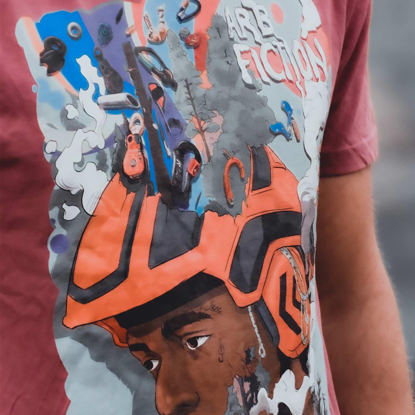 Close-up of a red T-shirt with the same colorful print of a man in an orange helmet and the text "ARB FICTION", product name Mind Fuck