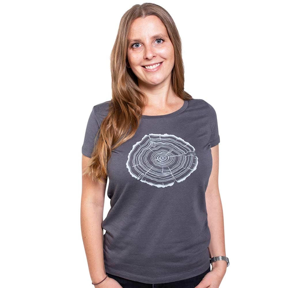 A woman with long blonde hair wears a gray Treeslice Women T-shirt with white tree trunk cut design on the front