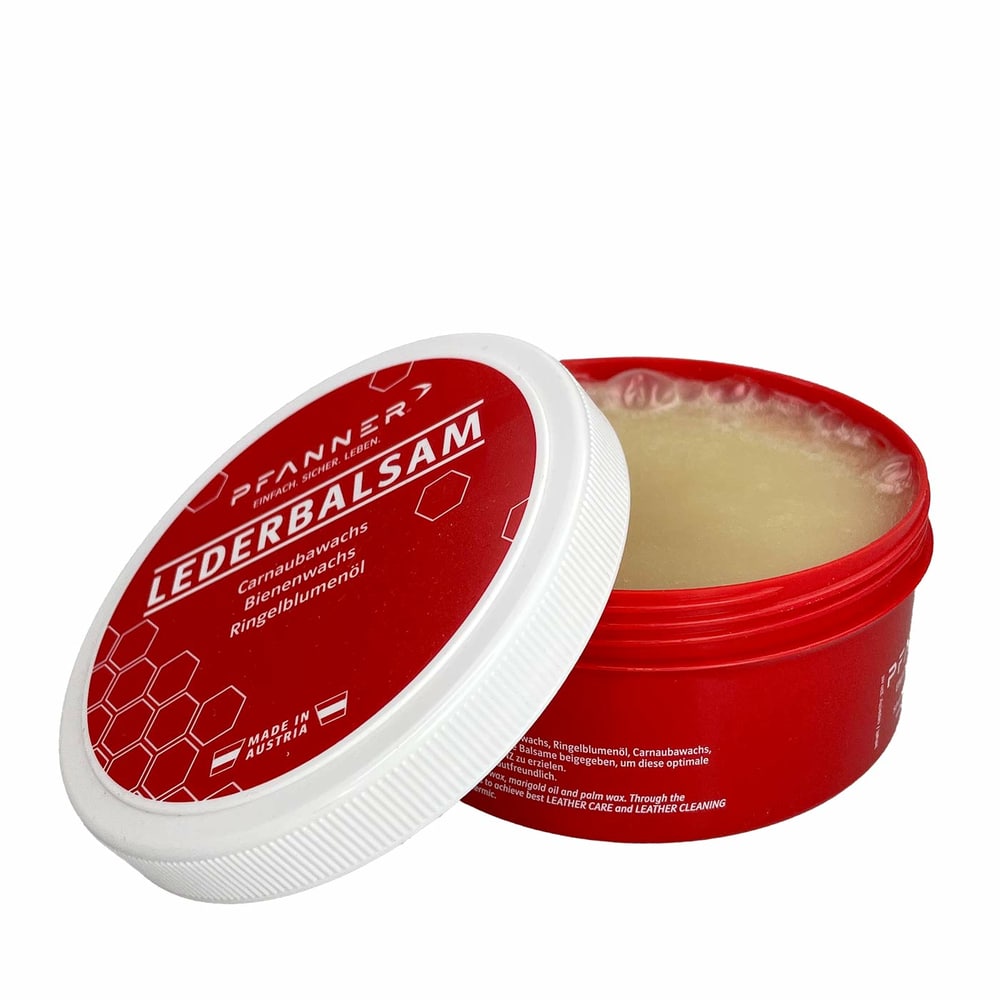 Pfanner organic leather balm in red round plastic container with open white screw lid, visible light yellow balm, inscription Leather balm and ingredients, made in Austria