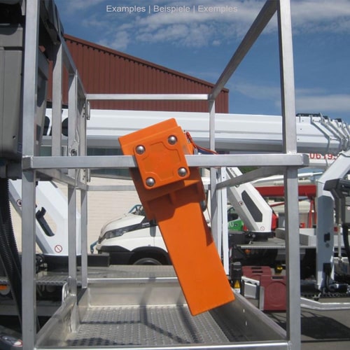Orange mounting plate universal mounted on a silver metal frame, vehicles and buildings in the background, outdoor shot in daylight