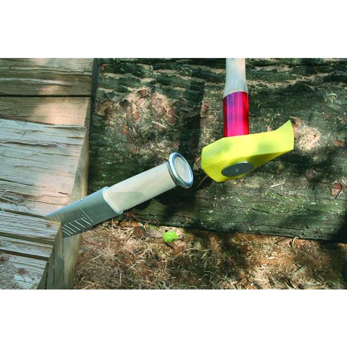 Alu 360, tool with aluminum blade and light wooden handle with metal finish, next to it a hammer with a red handle and yellow protective cap, both lying on wood and earth