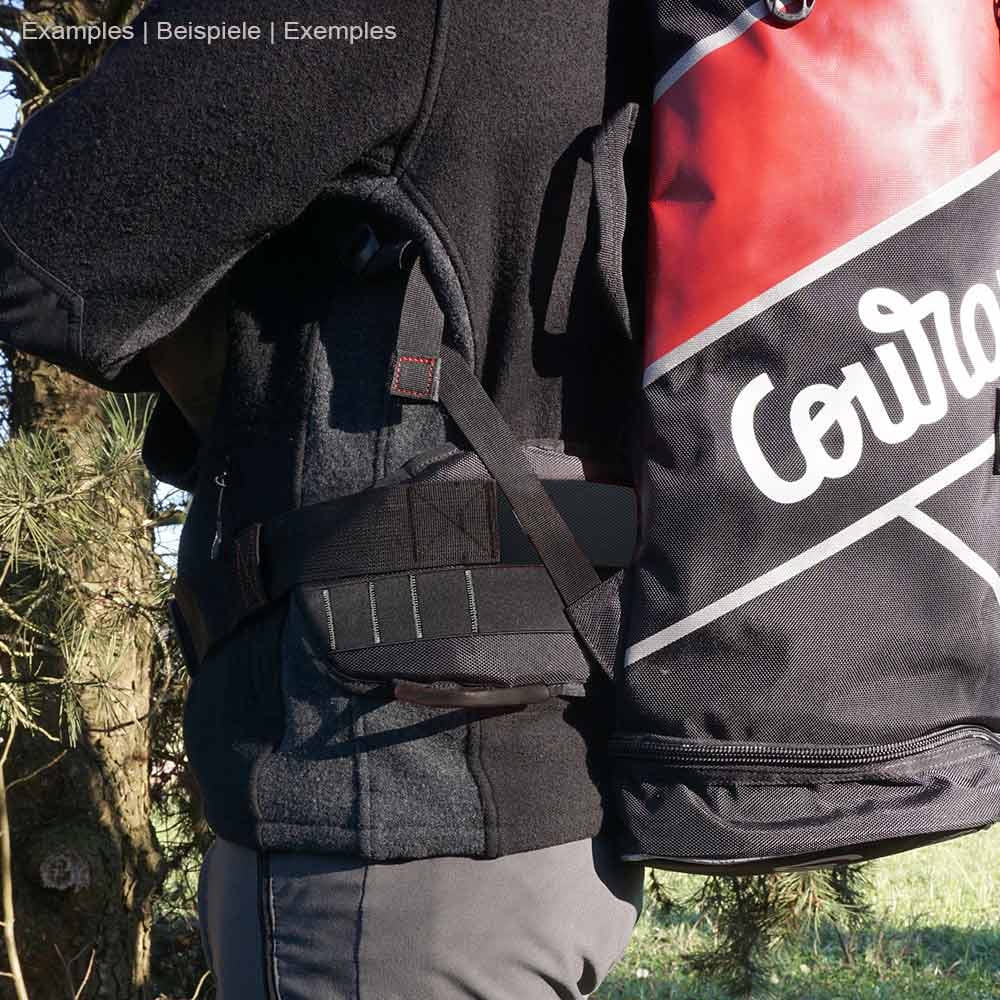Person wearing black cross belt with white lettering "Courant" and red backpack, manufacturer not visible