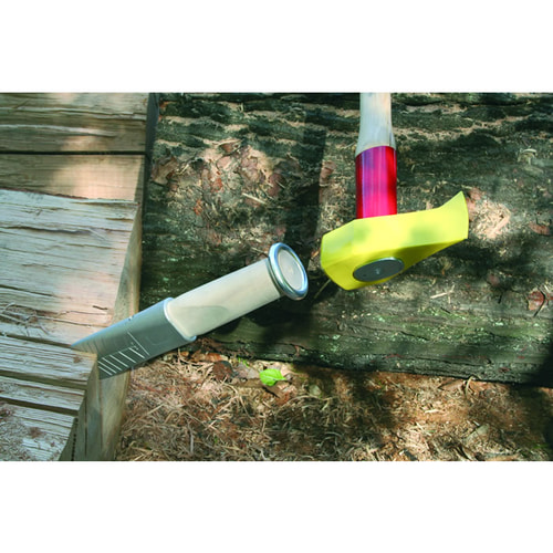 Alu 360, tool with aluminum blade and light wooden handle with metal finish, next to it a hammer with a red handle and yellow protective cap, both lying on wood and earth
