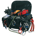 Multiuse bag in black opened with various climbing equipment such as carabiners, helmet and ropes inside