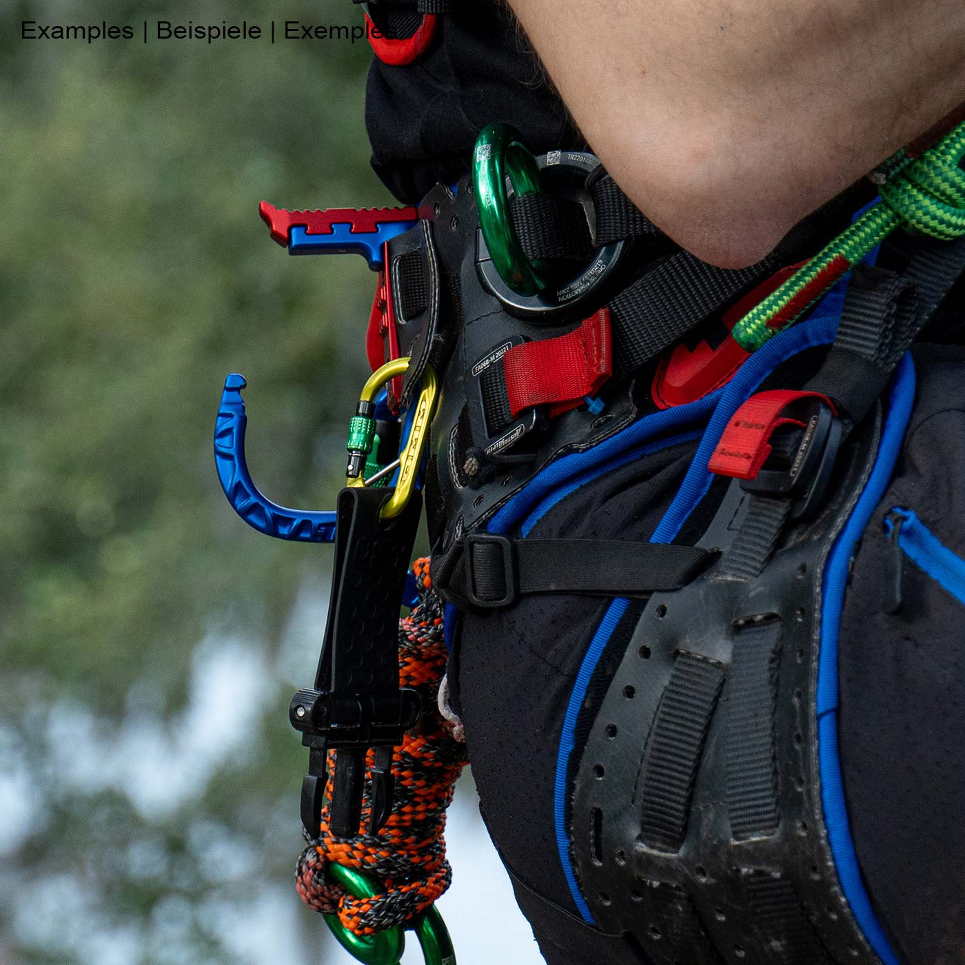 skyHOOK Open Gate in blue and red attached to a climbing harness, in use by a person with climbing equipment