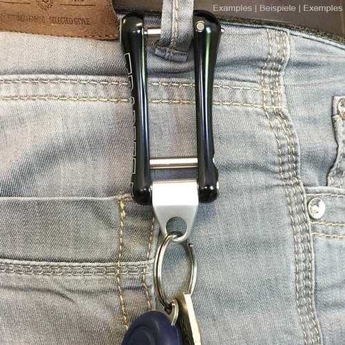 Trapezoid metal eye engraved with ART, attached to a black plastic trapezoid hanging from a belt with key ring and keys