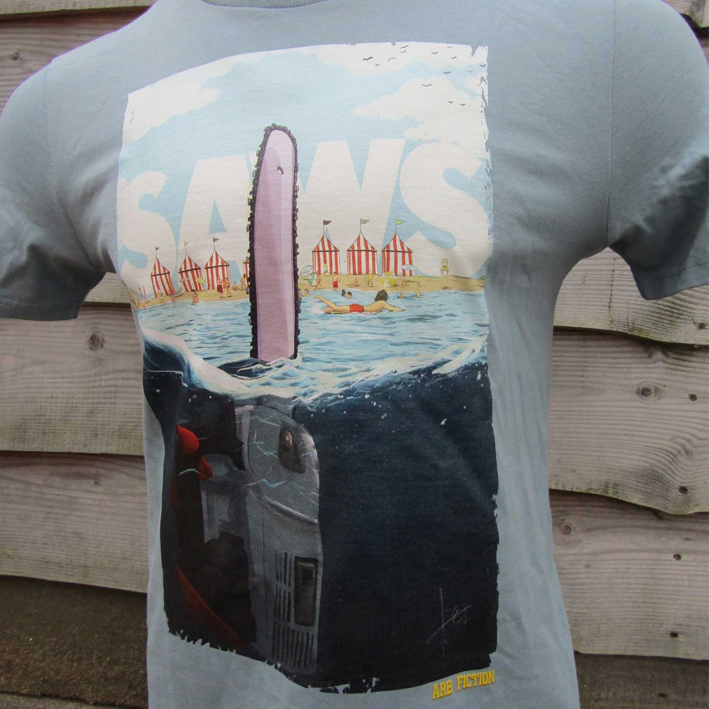 Gray T-shirt with a large print of a free-floating chainsaw in the water, above it the lettering "SAWS" and in the lower area the text "ARB FICTION".