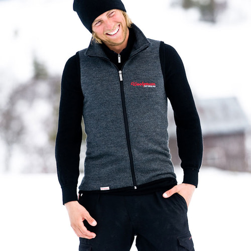 Vest 400, gray sleeveless vest with zipper, worn by a smiling man with a black cap and black undershirt, red Woolpower Östersund logo on the chest