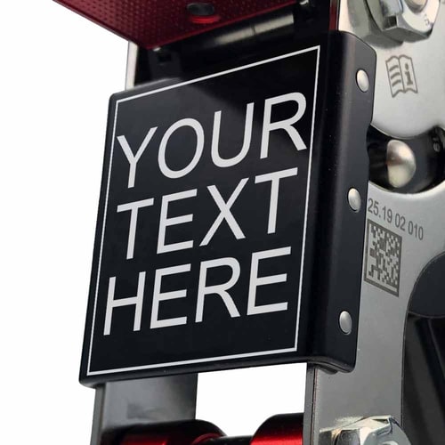 Close-up of the text board with the inscription "YOUR TEXT HERE" on the SpiderJack 3 – laser text climbing frame, visible screws and QR code on the silver frame