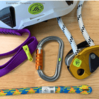 Climber Pack NFC tag with climbing equipment such as carabiners, ropes and webbing, partly covered with green Scannable stickers, on a wooden table