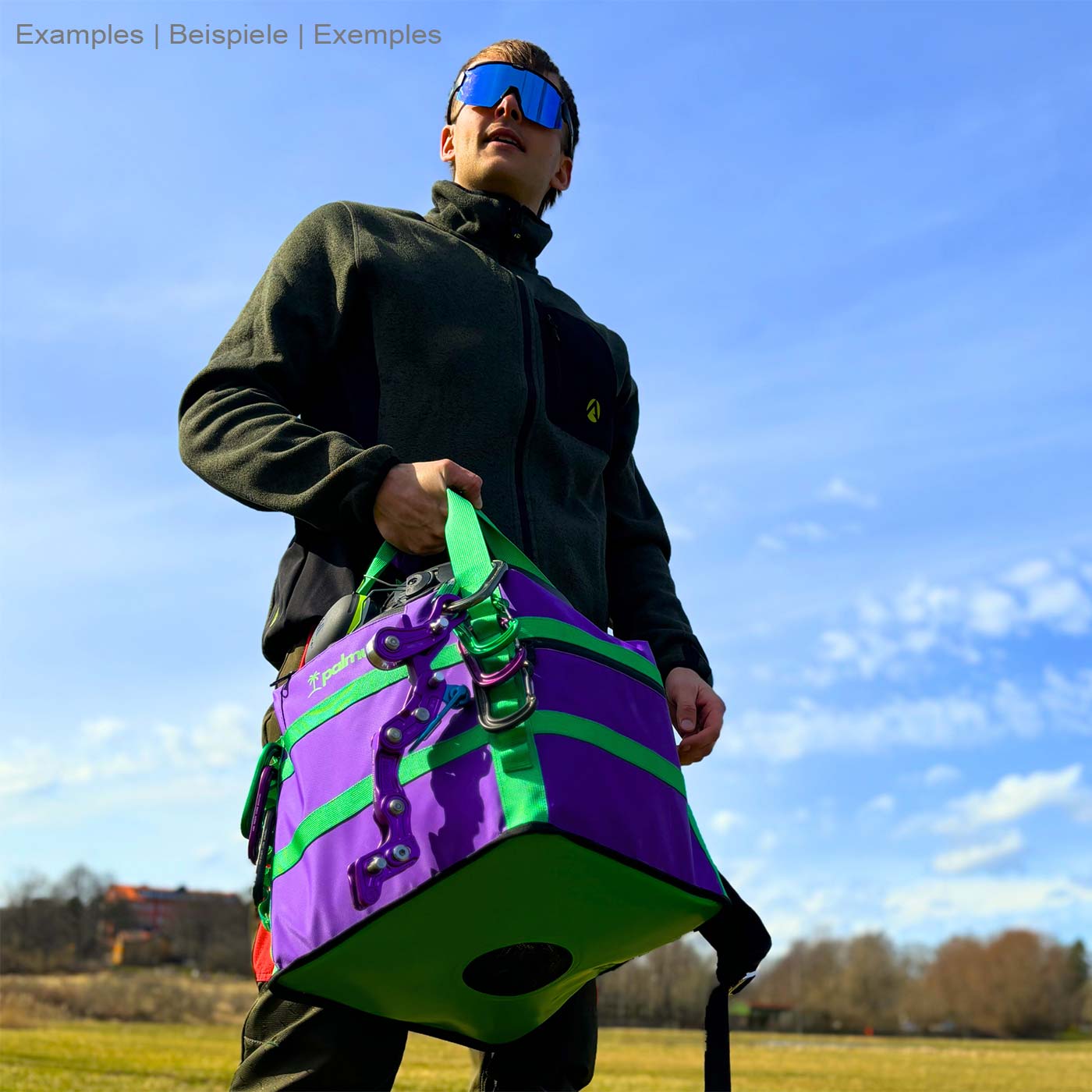 Person carrying Palmu 32 bag in purple and green in hand, manufacturer Palmu visible