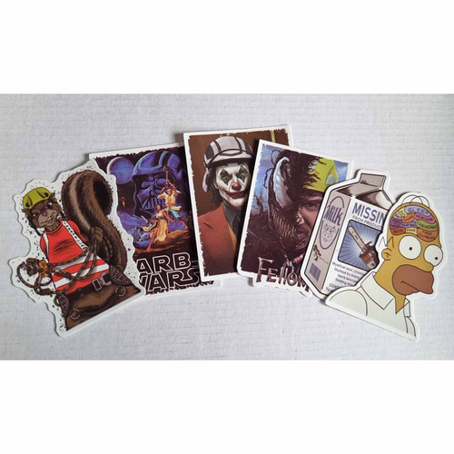 Several colorful stickers from the ARB Fiction Pack Vol. 4, including a squirrel with helmet, an ARB WARS poster, a Joker with a red suit, a milk carton with a chainsaw, a half Venom with a construction helmet, and a Homer Simpson head with thought bubble