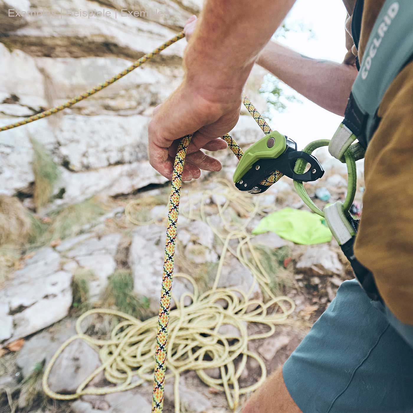 Person with climbing frame Pinch from Edelrid in black and green on climbing harness, holding yellow rope in hand