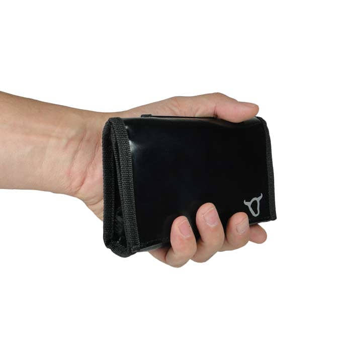 Black belt pouch with black rim and white bull's head logo, held in one hand