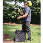 Man in yellow helmet and sunglasses standing on grass and holding orange rope over a black Pro Folding Cube of Notch