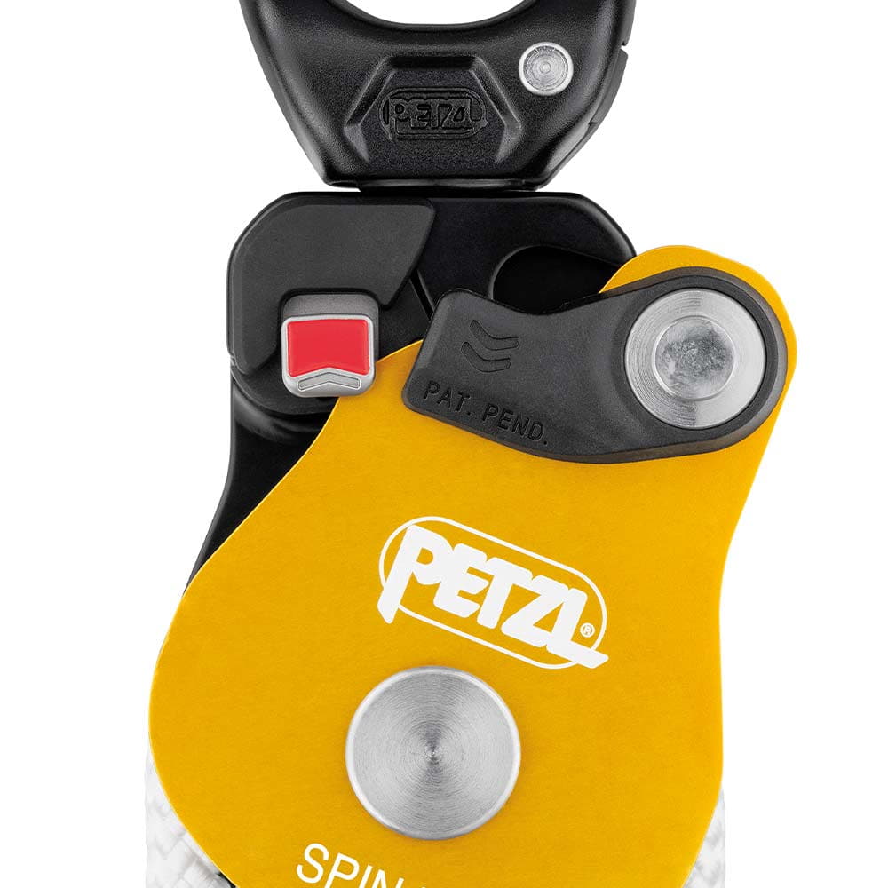 Close-up of the Petzl Spin L2 block with yellow housing, white PETZL logo, red switch and black snap hook