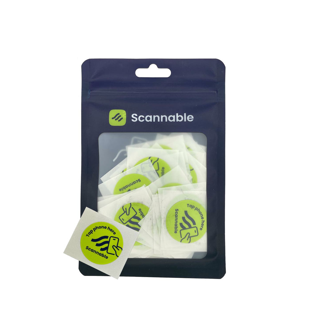 Packaging with several round, yellow helmet stickers NFC tag stickers with black inscription "Tap phone here Scannable" and a smartphone icon