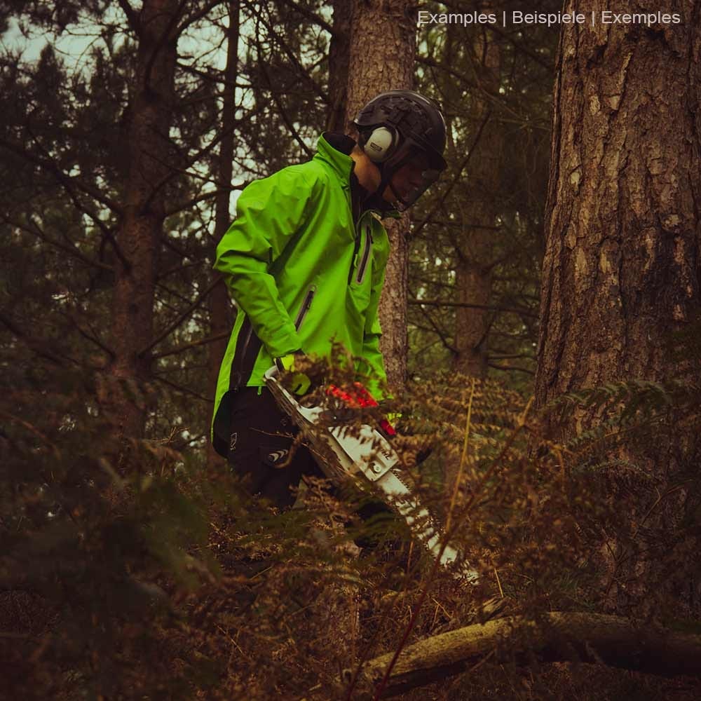 Person wearing green BreatheDry smock jacket with black pants and helmet in the forest, holding a chainsaw