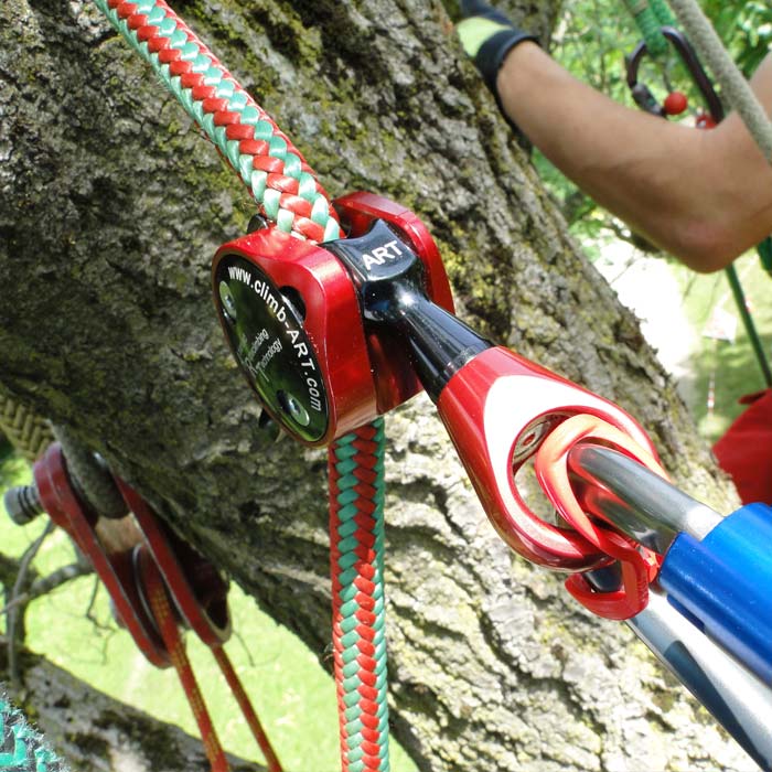 Positioner 2 by Climb Art, red and black climbing positioner attached to a red and green braided rope on a tree