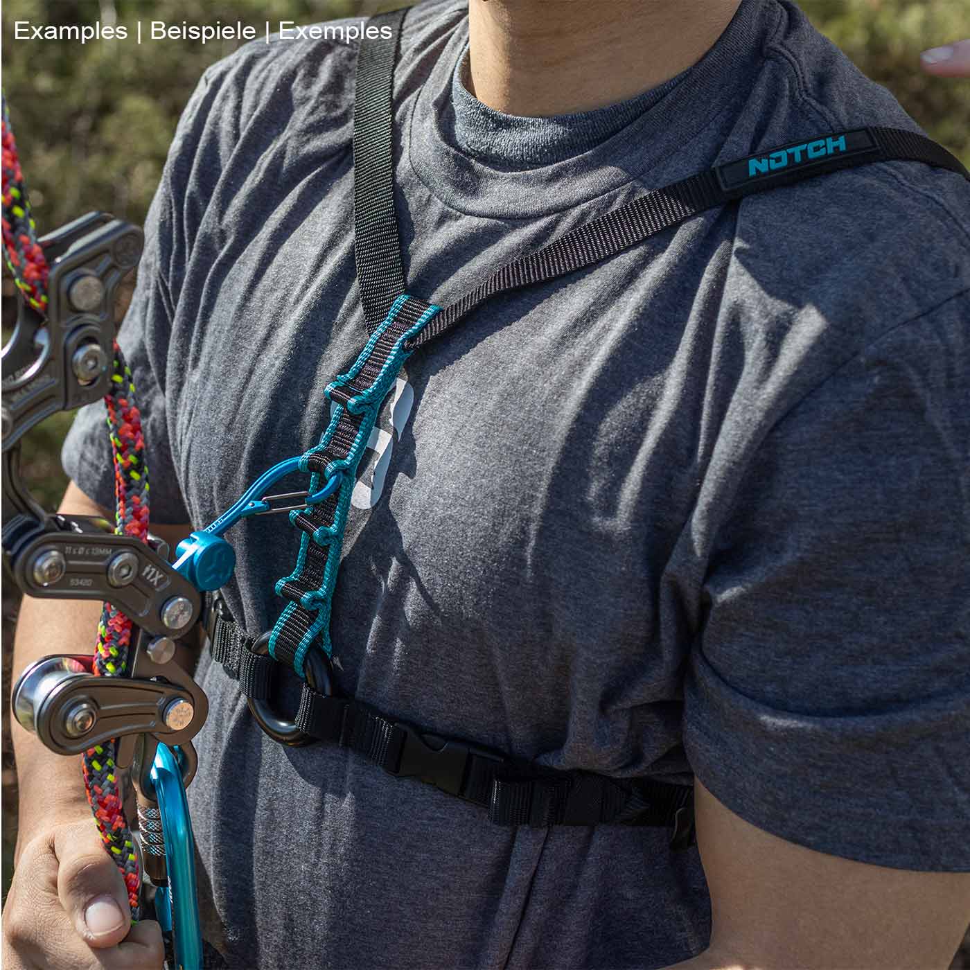 Person wearing a gray T-shirt and a black Chester SRS chest strap with turquoise stitching, holding climbing gear in his left hand
