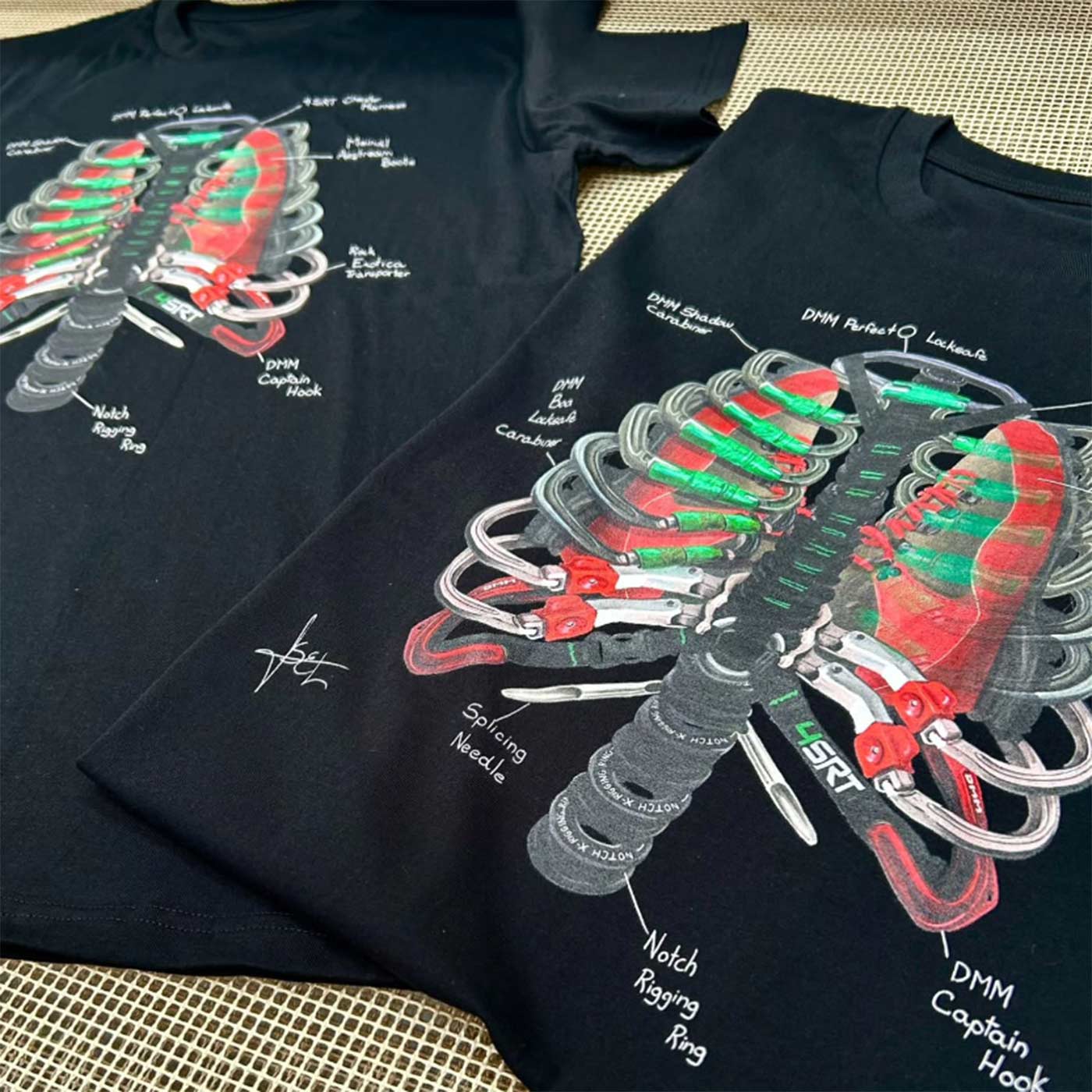 Two black Arb Ribs T-shirts with the rib cage pattern printed on them from climbing equipment lie next to each other on a surface