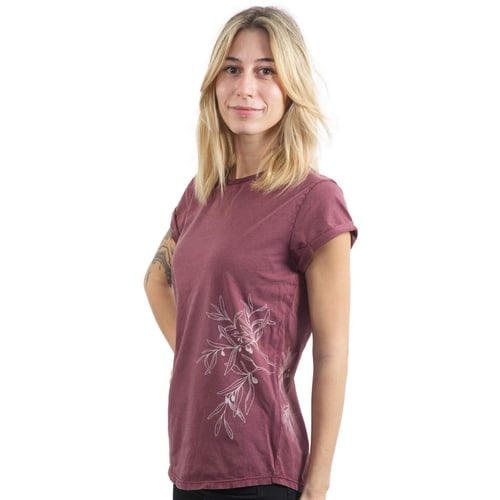 A woman wears a burgundy T-shirt "Olive Branch" with a white olive branch motif on the side and has her hands behind her back.