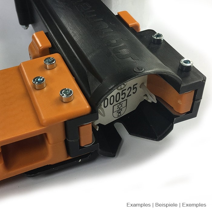 Detail of the opening of the black ArboTag Magazine Lite with orange plastic parts and visible serial number
