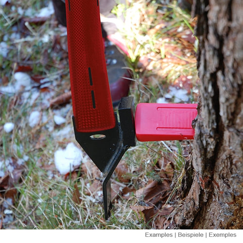 Felling jack 600 from Stubai in use, red handle and black metal tip on a tree trunk, ground with grass and leaves visible