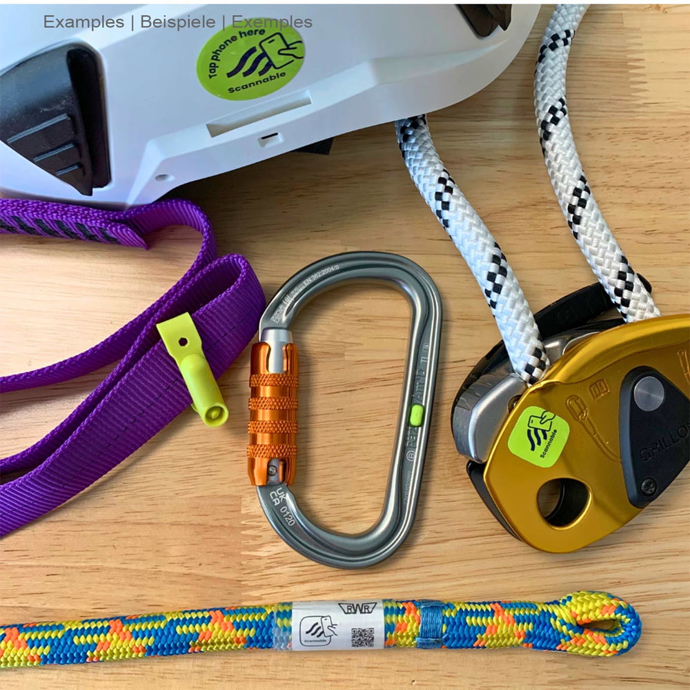 Climber Pack NFC tag with climbing equipment such as carabiners, ropes and webbing, partly covered with green Scannable stickers, on a wooden table