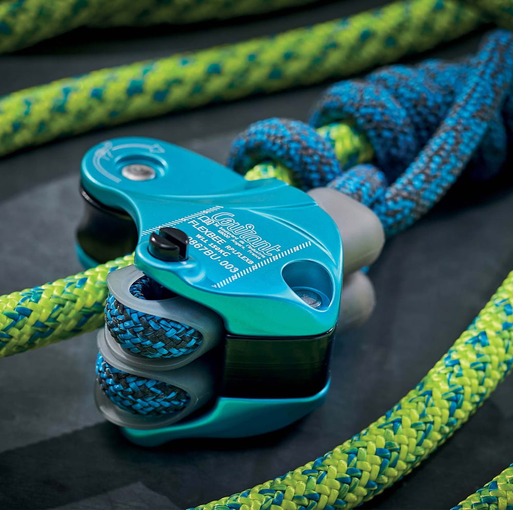 Flexbee close-up of blue belay device with blue and yellow climbing rope on black background